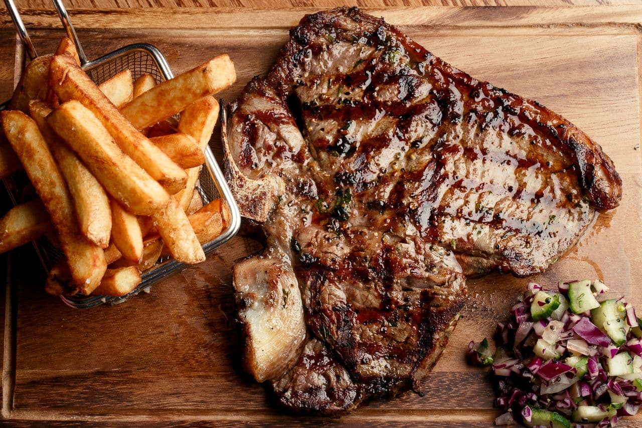 Raw steaks being prepared on the grill